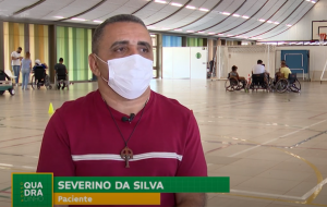 Severino da Silva, paciente do SARAH Brasília em entrevista à TV Câmara Distrital De camisa vermelha, o paciente e jogador de rugy em cadeira de rodas Severino da Silva fala sobre sua reabilitação. Ao fundo, na quadra poliesportiva do Hospital SARAH Lago Norte, outros cadeirantes conversam em grupos.