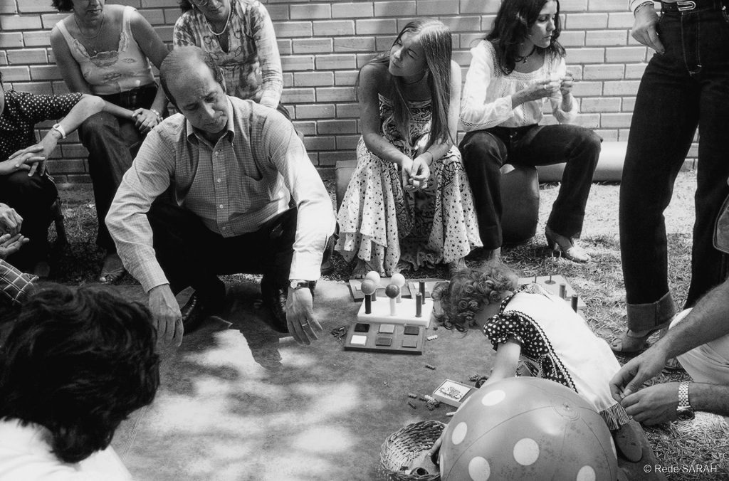 Dr. Aloysio Campos da Paz Júnior (à esquerda) e Dra. Lúcia Willadino Braga (à direita) com equipe interprofissional e pacientes, nos jardins do antigo Centro de Reabilitação