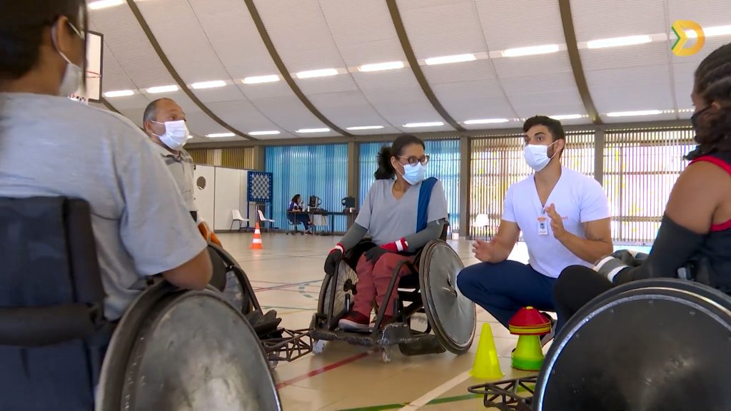 Na quadra poliesportiva do SARAH Lago Norte, professor de educação física, sentado, dá aula de rugby a paratletas, sentados em cadeiras de rodas.