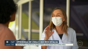 Dra. Lúcia Willadino Braga em entrevista ao DF1 (Captura de tela – crédito: TV Globo) De pé, trajando jaleco branco e usando máscara cirúrgica, a presidente da Rede SARAH, Dra. Lúcia Willadino Braga, dá entrevista a repórter, que aparece de costas e desfocada.