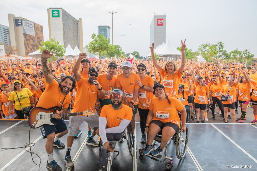 Ao fundo, da esquerda para direita, os atletas Aline Furtado, Caio Bonfim, Sérgio Fróes e a presidente da Rede SARAH, Lúcia Willadino Braga ao lado Diretora-Tesoureira Célia Corrêa. No centro, da esquerda para direita, o músico Jorge Recife, o locutor William Bonder, e os atletas Parré e Jade Lanai.
