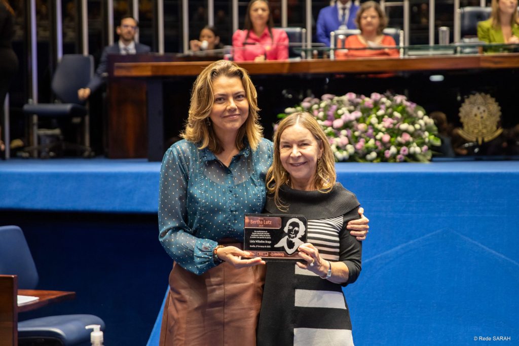 Senadora Leila Barros entregando condecoração à Dra. Lúcia